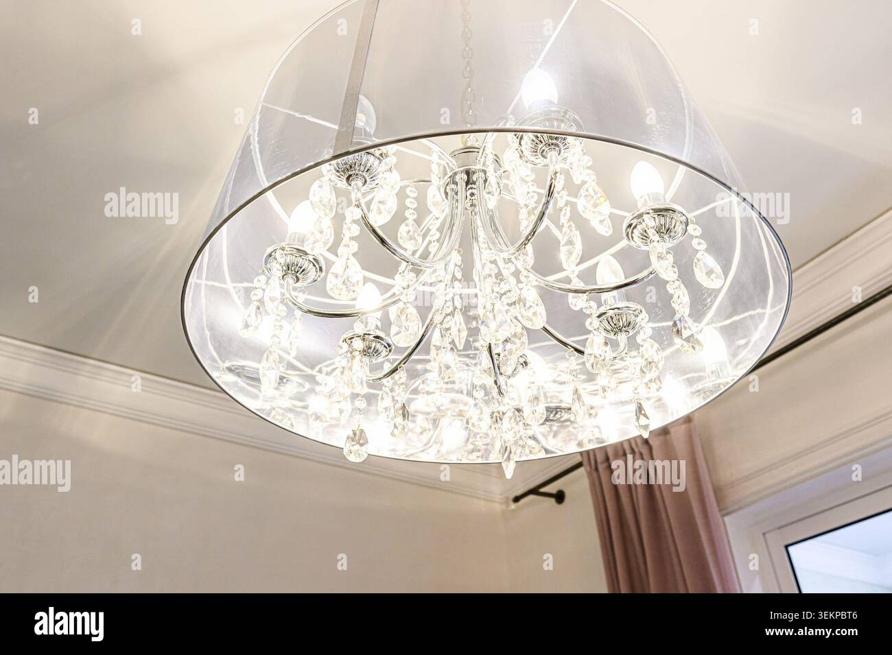 Elegante lampadario di cristallo con un paralume traslucido appeso al soffitto. Foto Stock