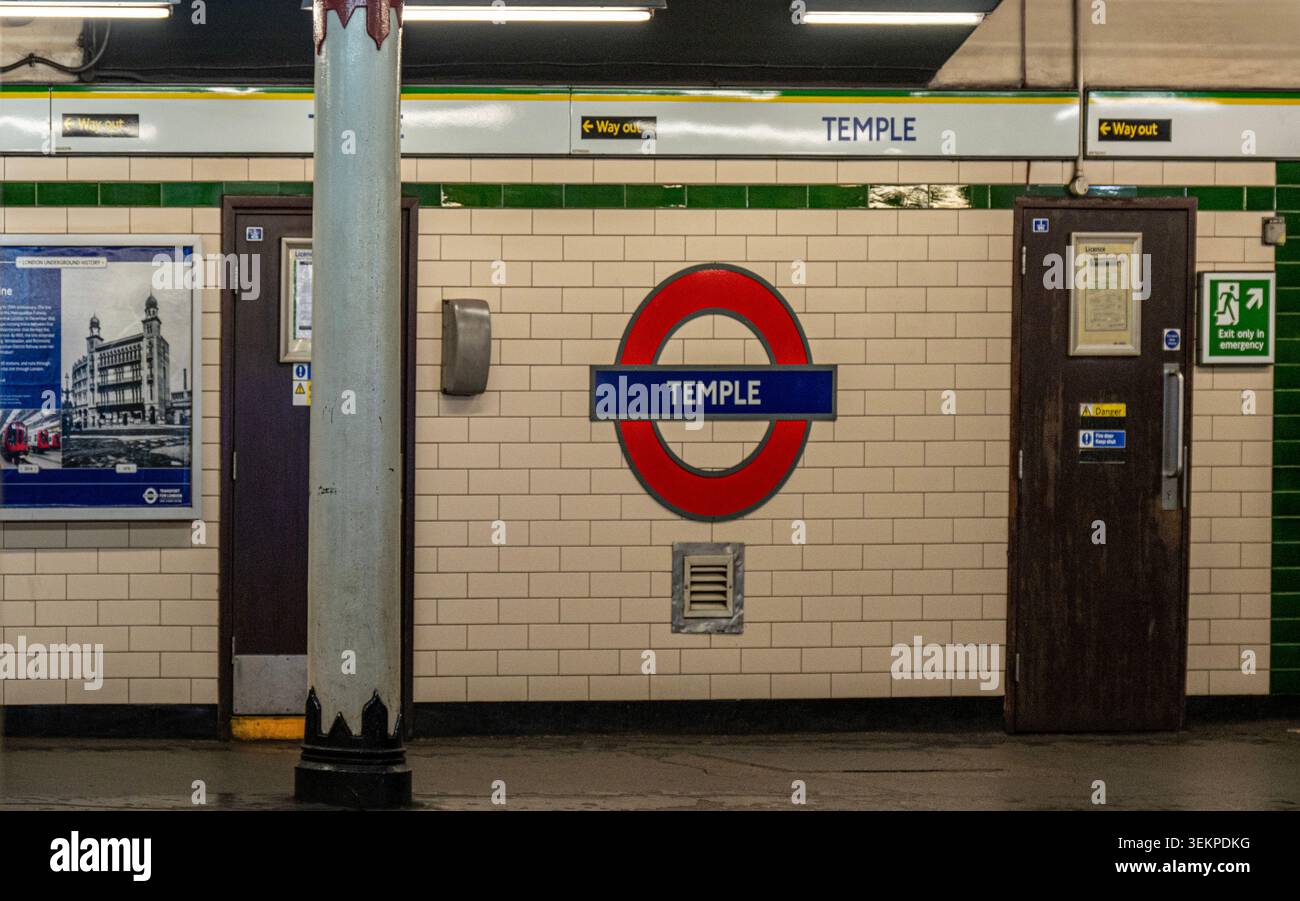 Piattaforma vuota della stazione di Temple sulla metropolitana di Londra, con un distintivo cartello rotondo rosso e blu. Foto Stock