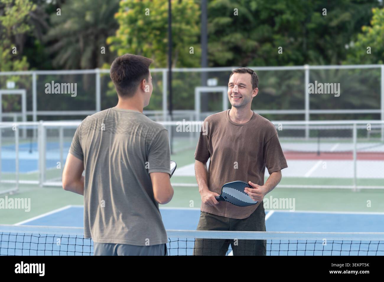 Persone attive e diversificate che giocano a Pickleball sul campo all'aperto Foto Stock