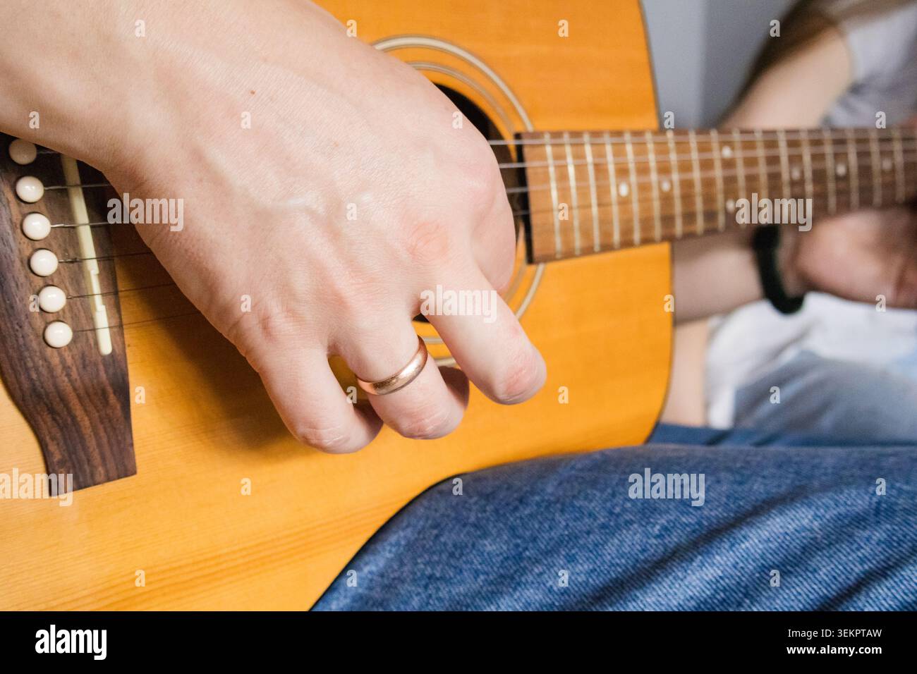 Primo piano di un uomo che suona la chitarra acustica al chiuso durante le esercitazioni di musica domestica. Hobby creativo, musica acustica e stile di vita per il tempo libero con Foto Stock