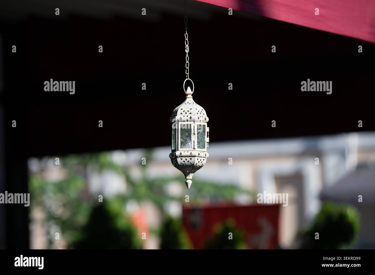 Lanterna decorativa bianca in metallo marocchino appesa all'esterno di una terrazza caffetteria. Lampada ramadan orientale vintage da vicino con sfondo esterno sfocato. Trad Foto Stock