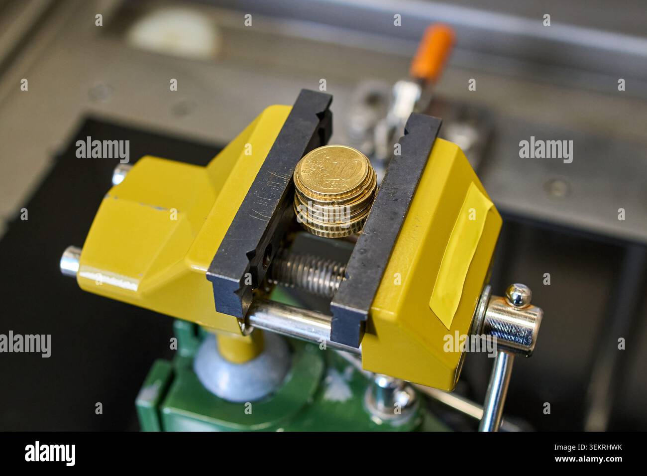 Financial Squeeze: Monete in euro compresse in un vizio giallo Foto Stock
