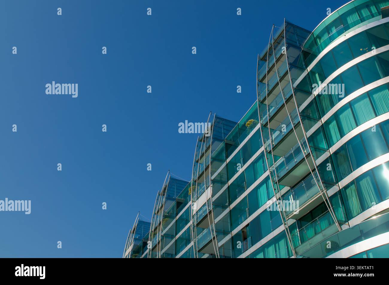 Vista architettonica ad angolo basso del futuristico Palazzo Mantegazza grattacielo curvo in vetro a Paradiso, Lugano. Eleganti finestre di cristallo blu e verde Foto Stock