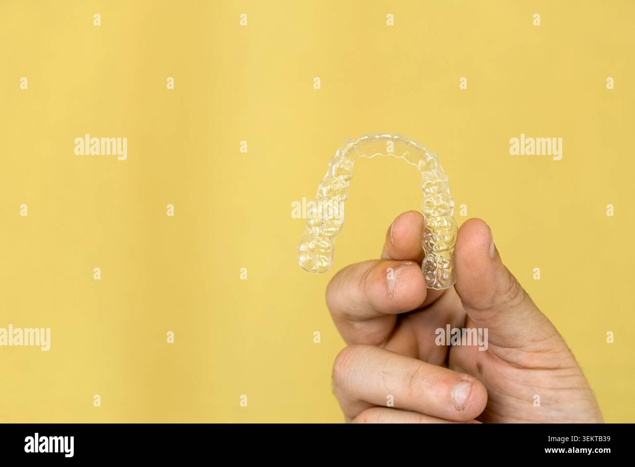 Mano che regge l'allineatore di denti in plastica trasparente Foto Stock