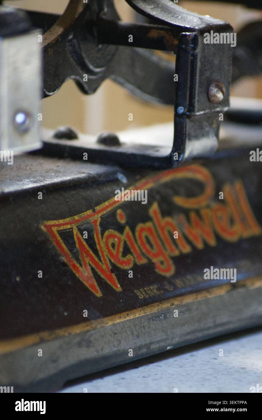 Prospettiva ravvicinata di un meccanismo di pesatura Weighwell vintage industriale pesante con struttura in ferro e lettere d'oro verniciate Foto Stock