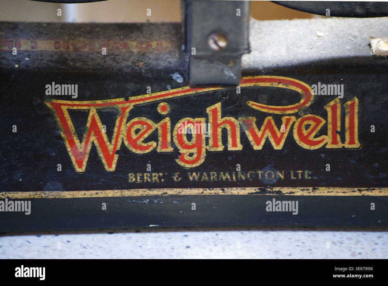 Foto macro di un cartello dipinto d'epoca con la scritta Weighwell Berry e Warmington Ltd. In oro classico e rosso Foto Stock