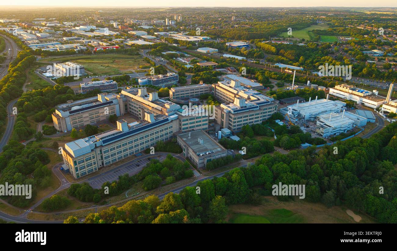 Vista aerea del campus di ricerca e sviluppo GSK Stevenage con moderni edifici di laboratorio circondati da lussureggianti alberi verdi e paesaggio urbano i. Foto Stock