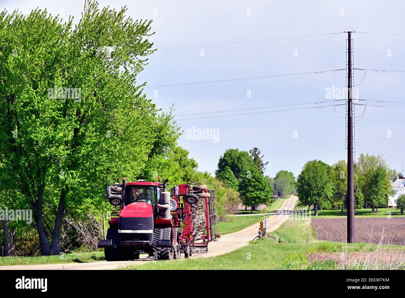Lee, Illinois, Stati Uniti. Un trattore tira macchinari mentre trasporta attrezzature tra i campi man mano che vengono piantati e coltivati. Foto Stock