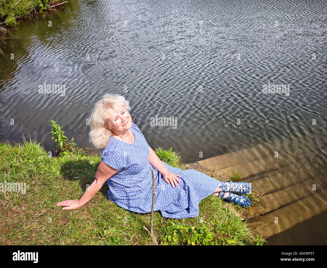 Donna bionda matura che si gode un momento tranquillo sul fiume durante la sua avventura di viaggio Foto Stock