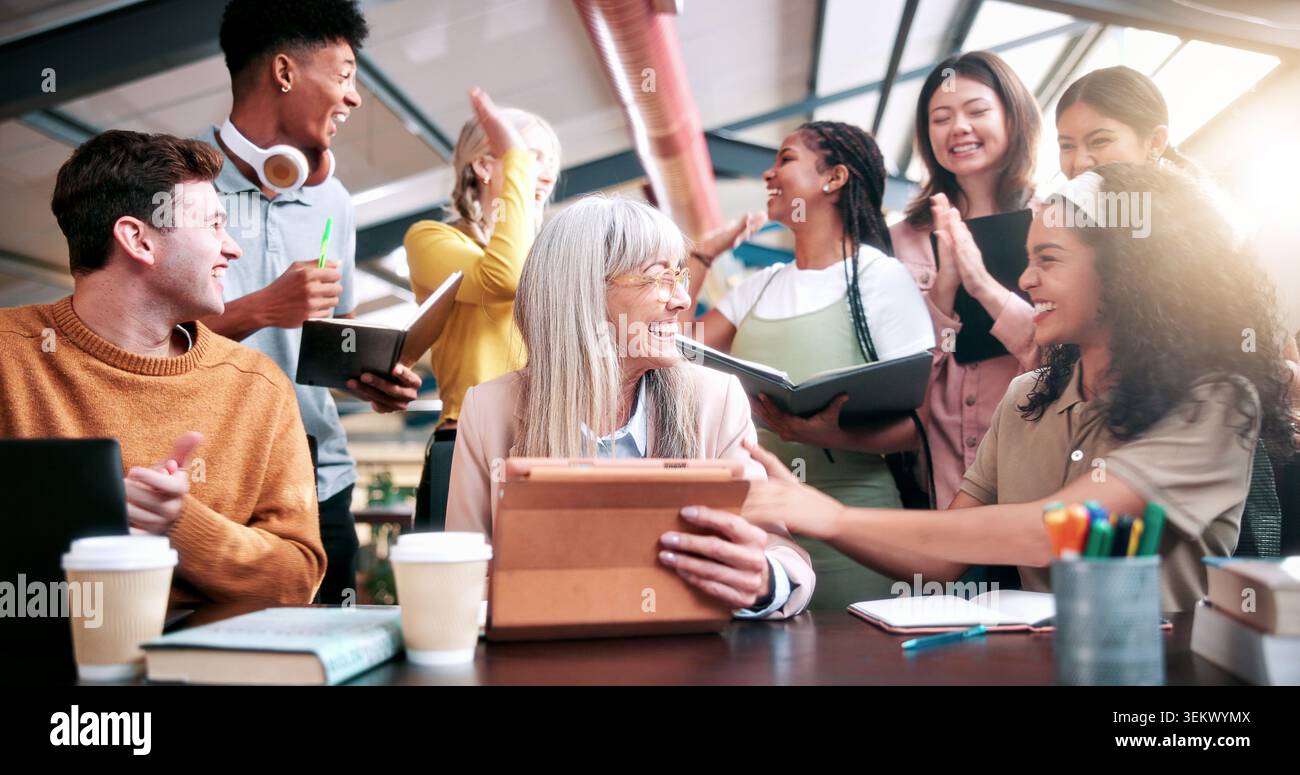 Celebrazione, istruzione e insegnante con gli studenti in biblioteca per applausi, alto cinque o successo. Apprendimento, tablet e università con persone entusiaste Foto Stock
