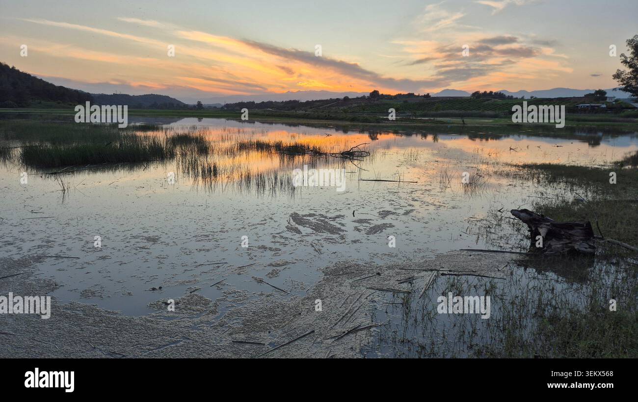 Paesaggio tranquillo al tramonto con riflesso del cielo vibrante sulla superficie dell'acqua calma al crepuscolo - Immagine stock catturata con smartphone