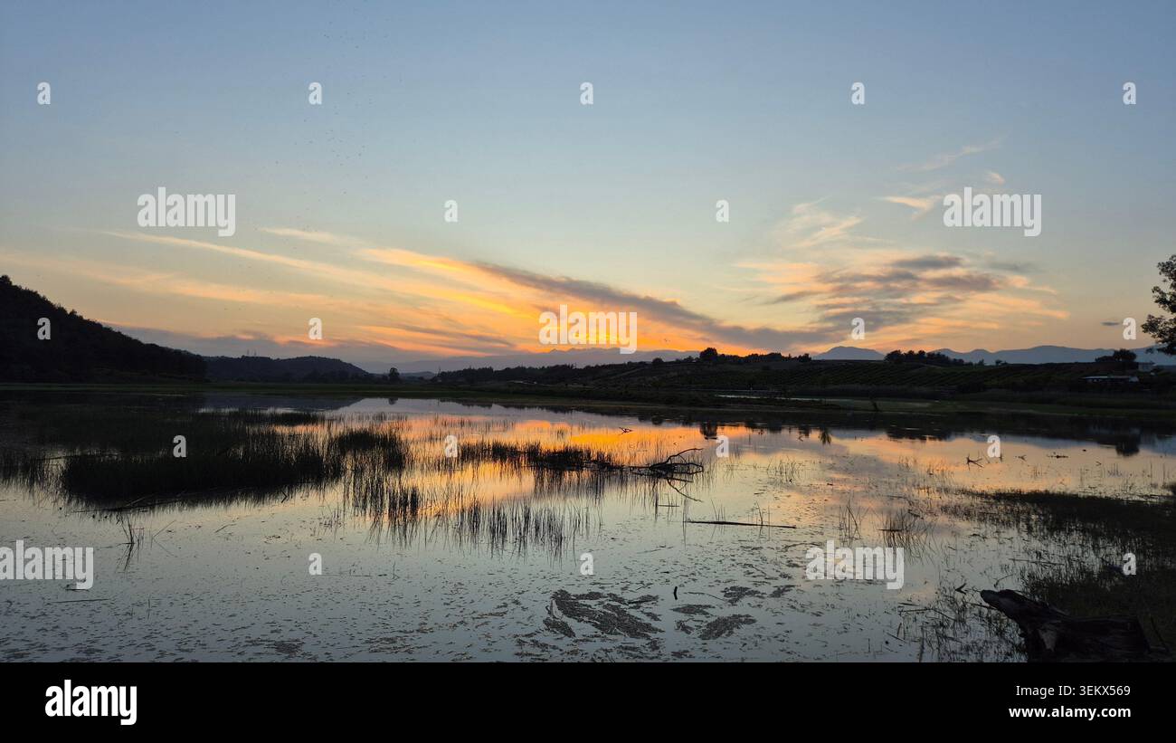 Paesaggio tranquillo al tramonto con riflesso del cielo vibrante sulla superficie dell'acqua calma al crepuscolo - Immagine stock catturata con smartphone
