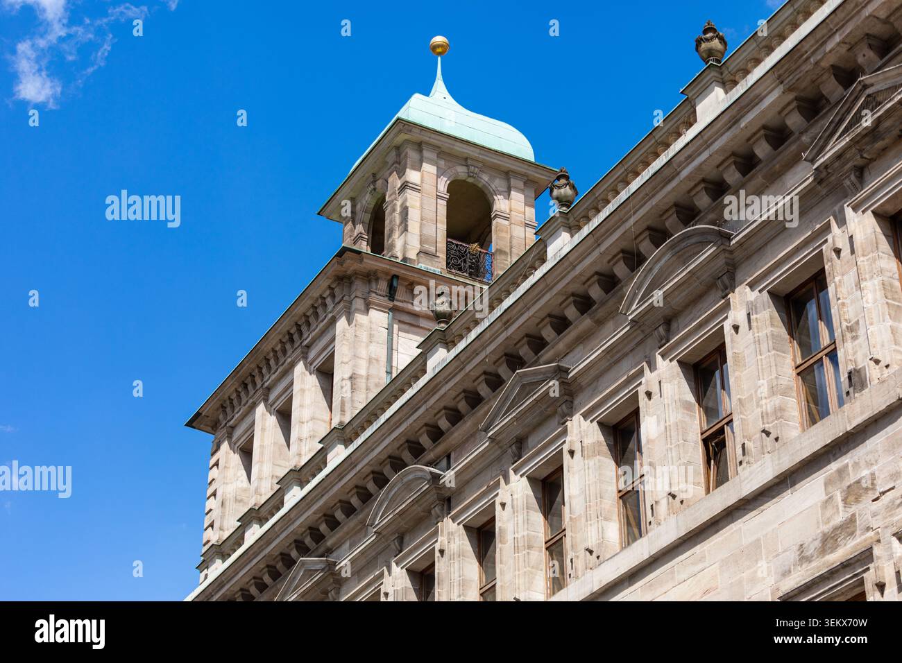 Elegante architettura rinascimentale caratterizzata da una torre con tetto in rame, facciata in pietra arenaria e dettagli classici su un cielo blu profondo. Foto Stock