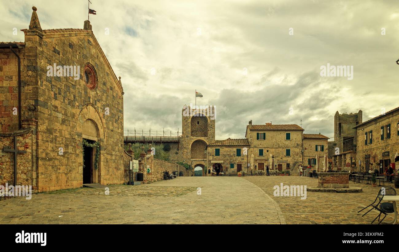 Castellina Scalo, Italia - 07.10.2021: Antica architettura romanica con mura in pietra intemprata e un'alta torre in una silenziosa piazza del paese italiano Foto Stock