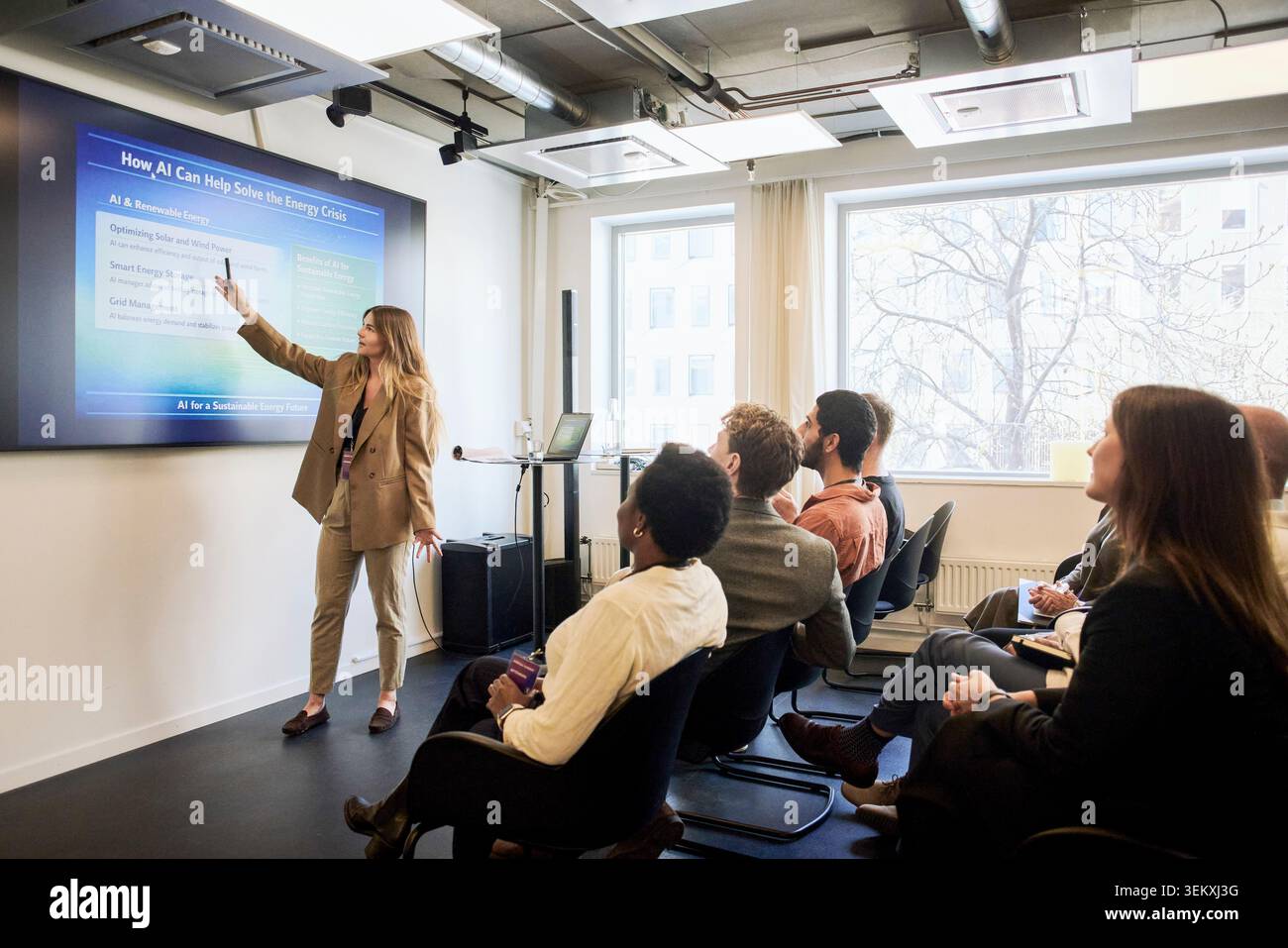 La presentazione completa di una presentatrice che spiega i punti della presentazione ai dirigenti aziendali attraverso lo schermo di proiezione in conferenza Foto Stock