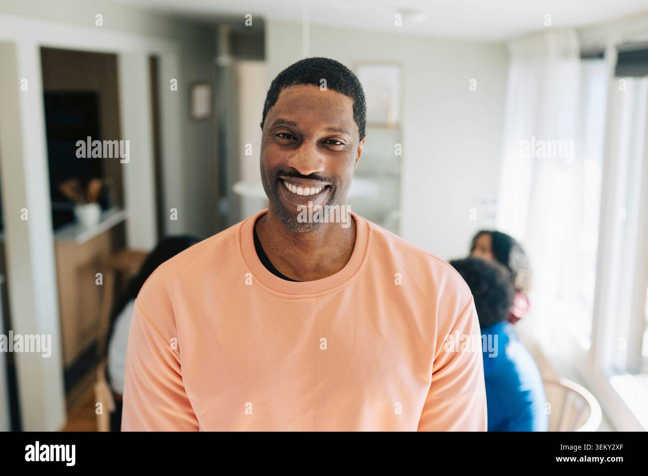 Ritratto di un uomo maturo sorridente che indossa una camicia color corallo a casa Foto Stock