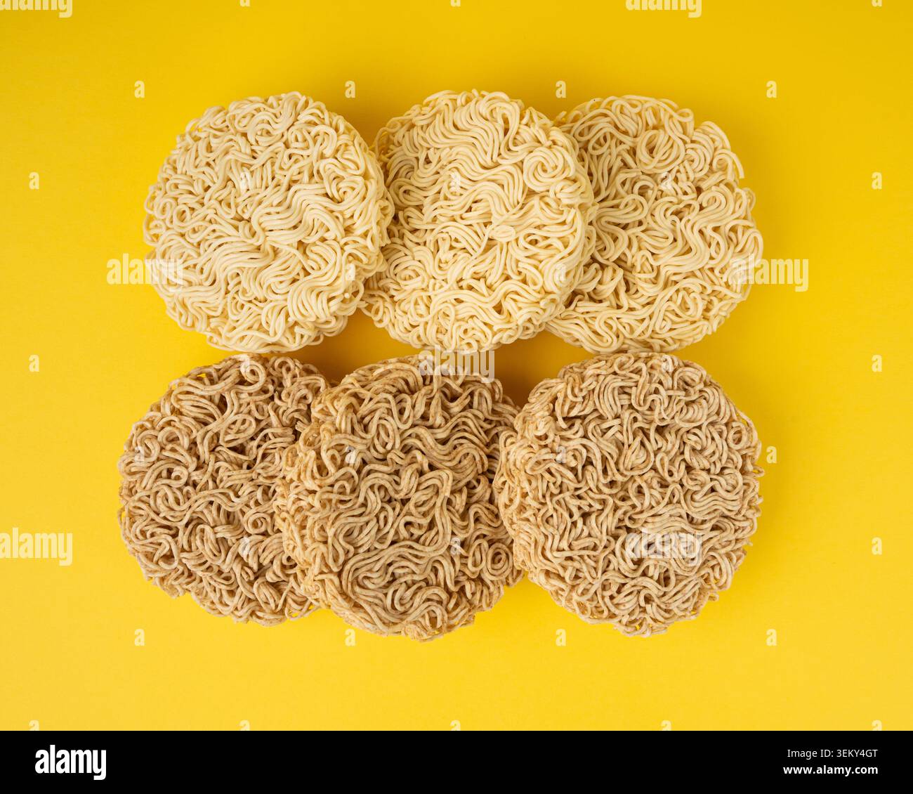 Tagliatelle crude, set di 6 tagliatelle Ramen rotonde asciutte, Vermicelli coreani crudi, pasta rapida di segale cinese e grano, maccheroni istantanei su sfondo giallo Vista dall'alto Foto Stock