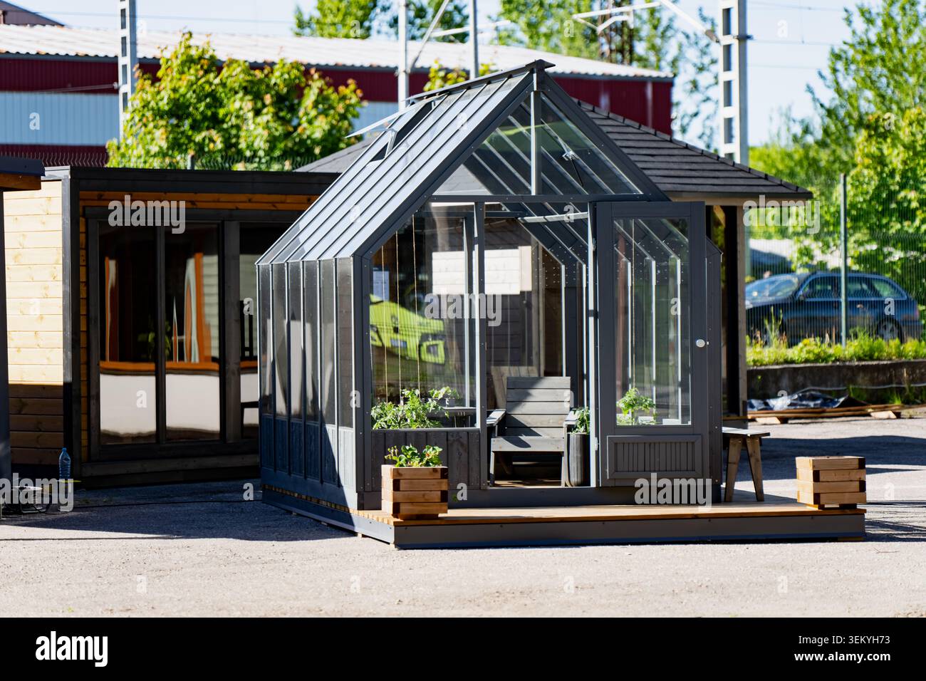 Padiglione giardino contemporaneo con pareti in vetro e mobili in legno esposti in un parco industriale che mostra il commercio e la produzione di negozi urbani Foto Stock