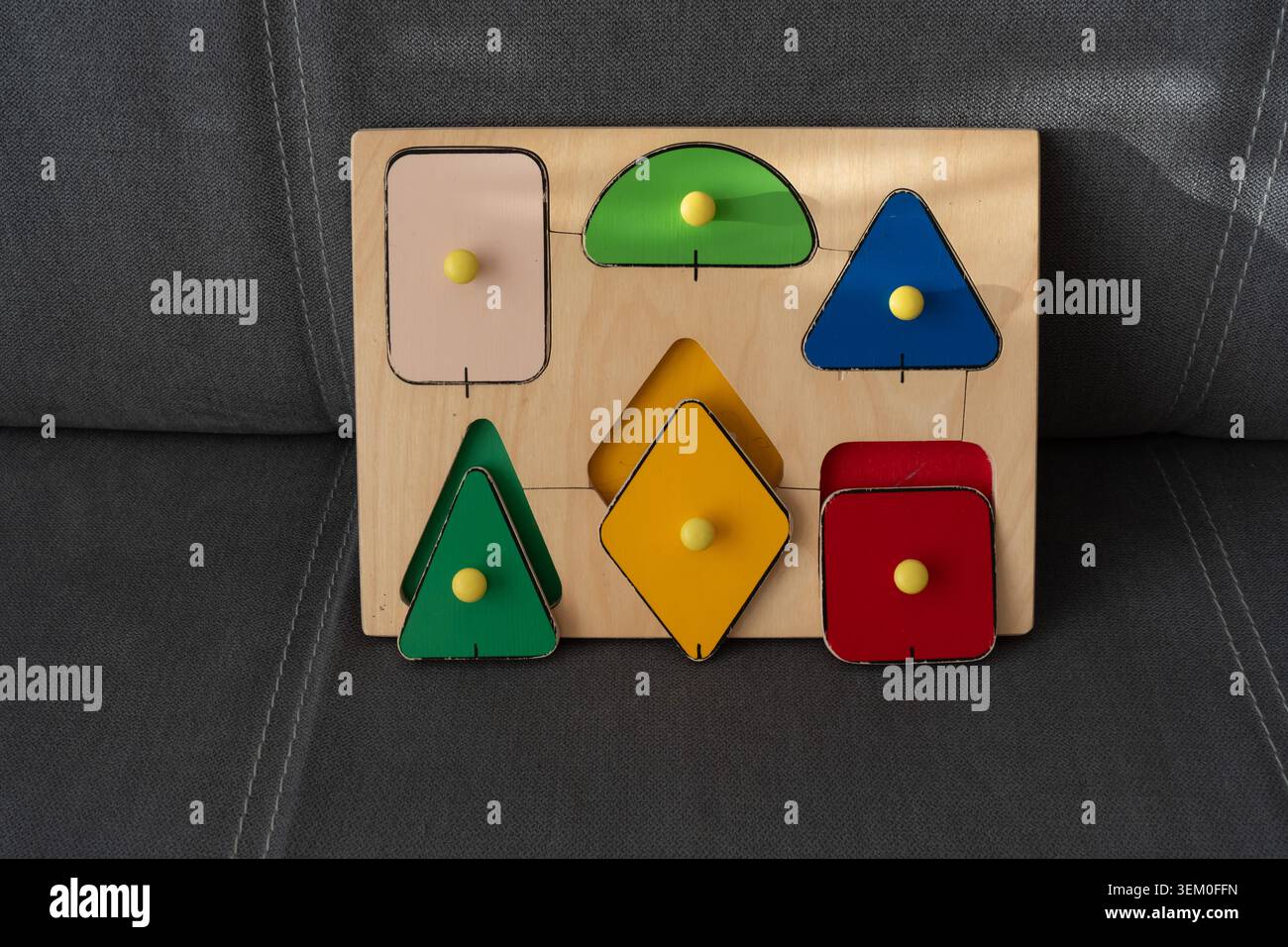 Tavola di selezione colorata in legno con pezzi geometrici triangolari, diamanti, quadrati e semicerchio. Concetto di educazione della prima infanzia, bambino Foto Stock