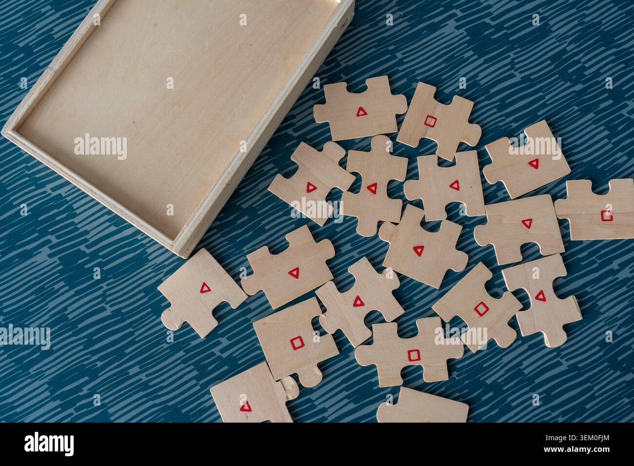 Pezzi di puzzle in legno con triangolo rosso e simboli quadrati posizionati accanto alla vista dall'alto della scatola di legno aperta. Concetto di gioco cognitivo, apprendimento della forma e. Foto Stock
