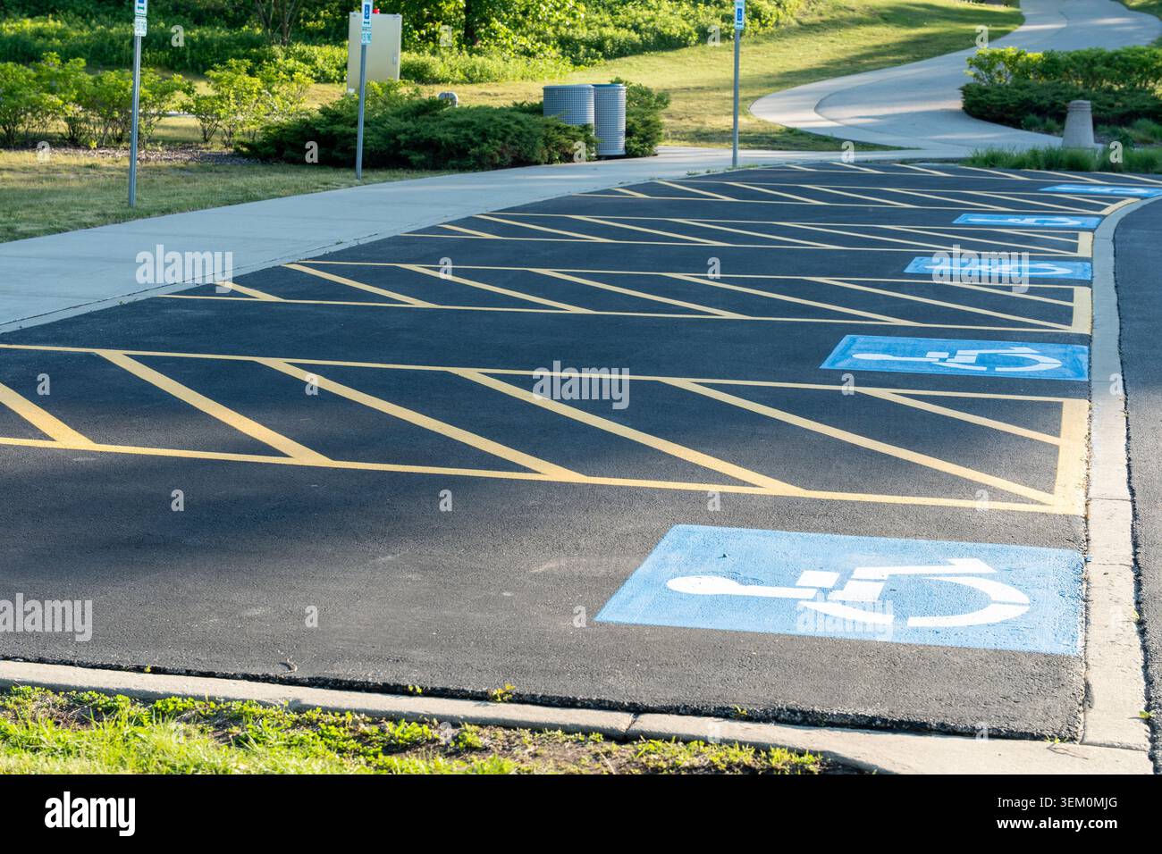 Foto orizzontale di un parcheggio con più posti auto per disabili contrassegnati con simboli blu per sedia a rotelle, evidenziando il design di accessibilità Foto Stock