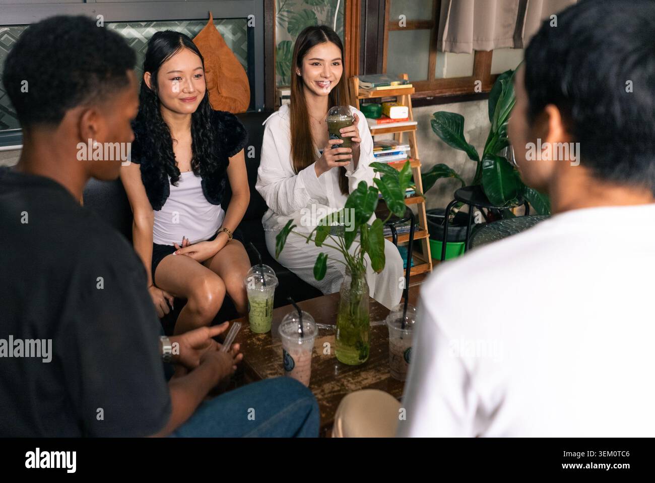 Amici giovani e diversi che si godono una rilassante conversazione di gruppo al bar Foto Stock