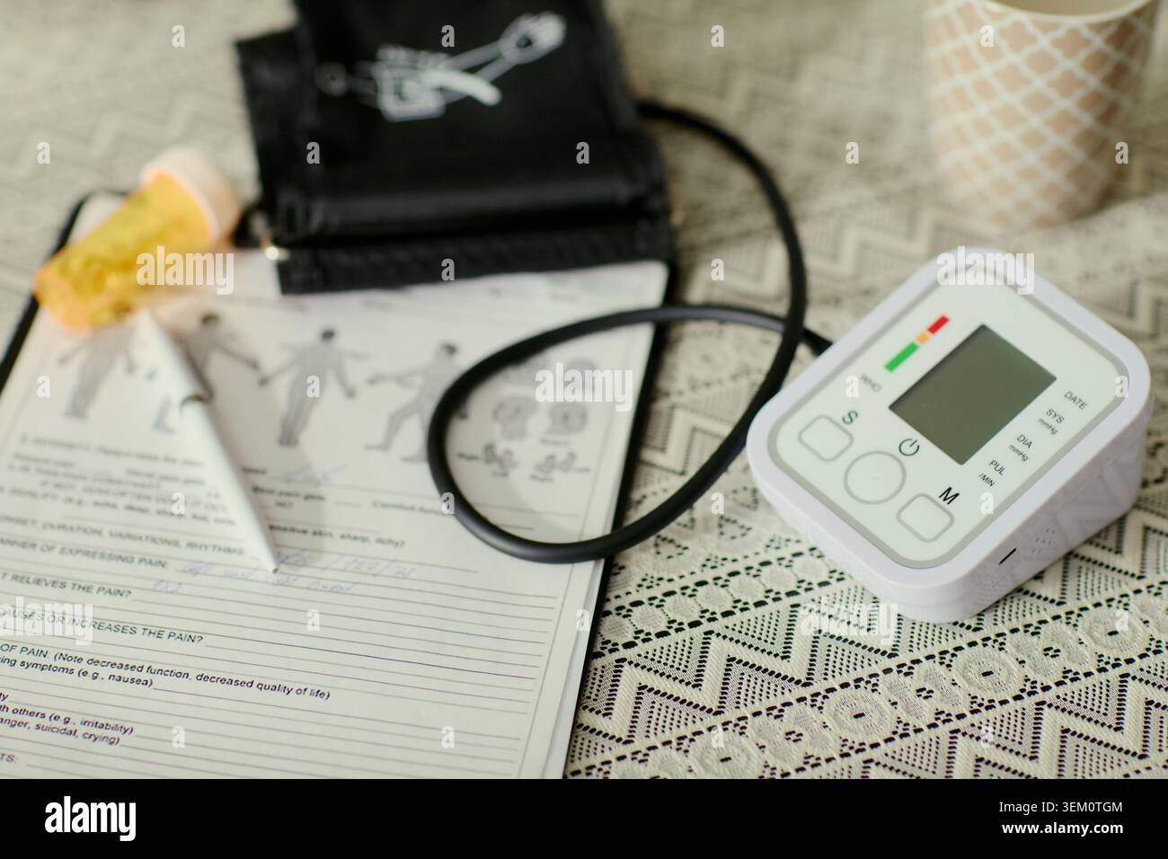 Primo piano degli strumenti medici di assistenza domiciliare che supportano il monitoraggio sanitario senior, mostrando dispositivo di pressione sanguigna, farmaci, documenti. Utile per la cura degli anziani, la cura della salute, il marketing per il benessere domestico Foto Stock