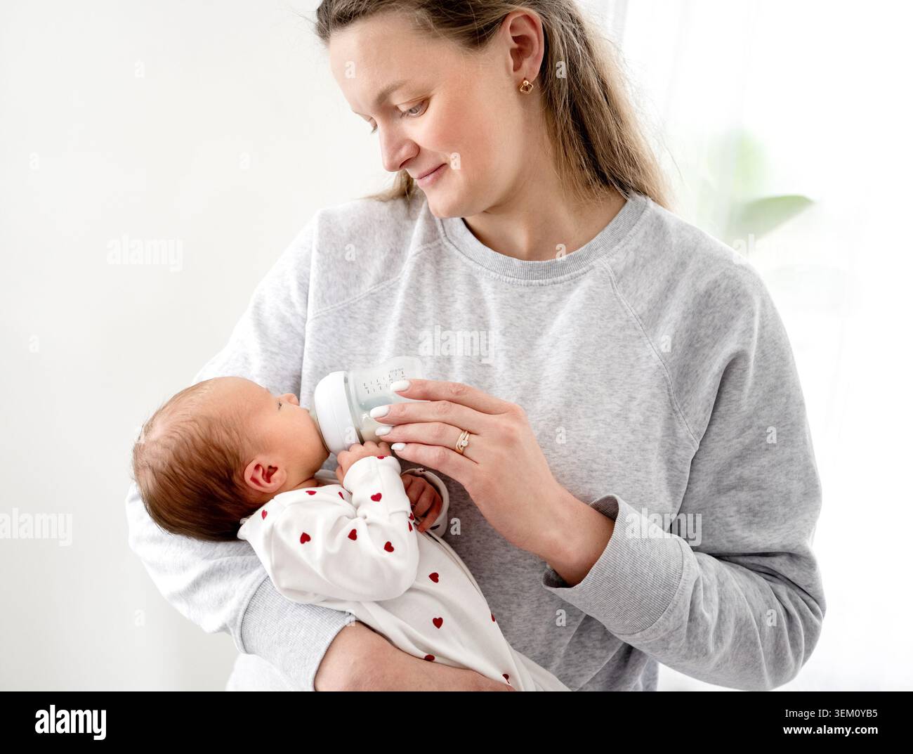 Neonata bambina che mangia tra le braccia della mamma Foto Stock