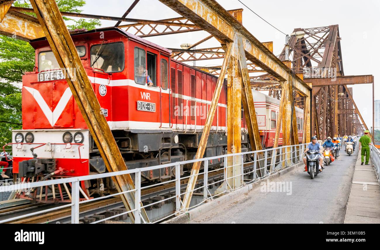 Hanoi, Vietnam - 11 giugno 2025: Un treno ferroviario vietnamita si avvicina alla stazione ferroviaria di Long Bien, dopo aver attraversato la trave in acciaio coloniale francese b Foto Stock