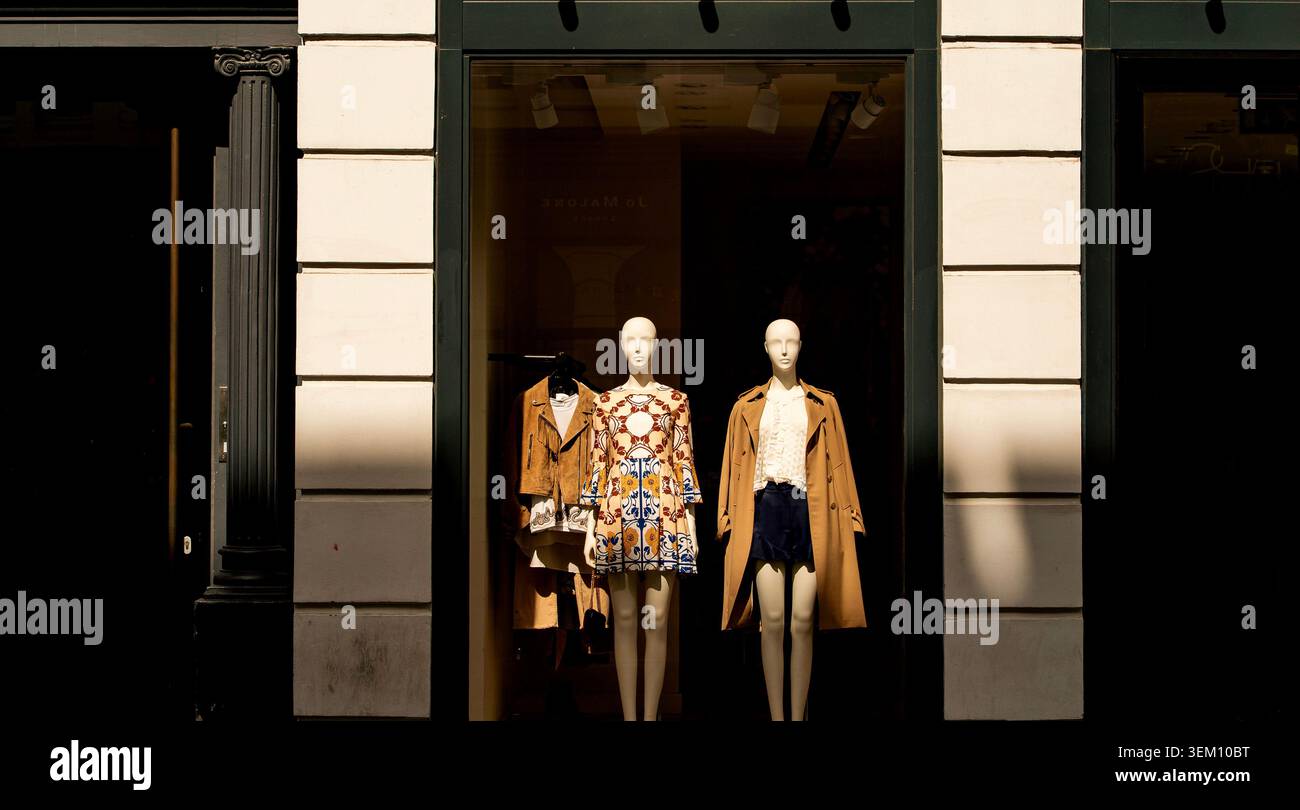 Due manichini di moda che espongono abbigliamento firmato in una vetrina di un negozio di lusso Foto Stock