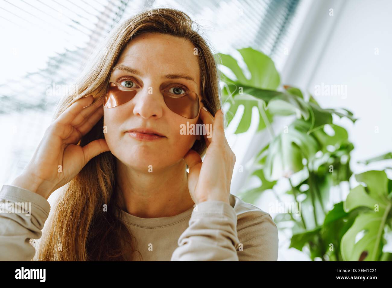 donna di mezza età con lunghi capelli biondi e macchie sotto gli occhi Foto Stock
