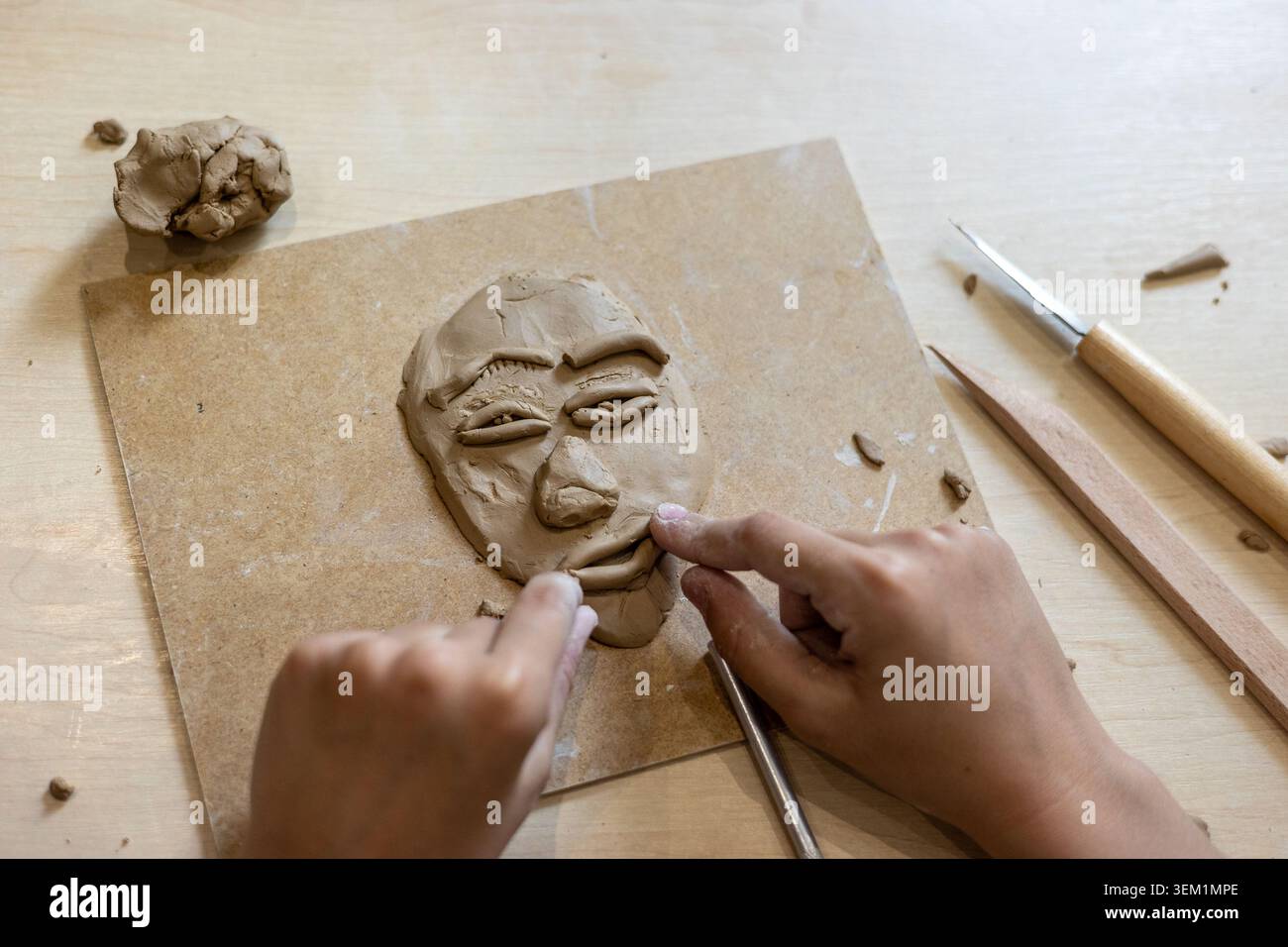 le mani dei bambini modellano un viso di argilla durante l'attività artistica creativa. Arte terapia, espressione emotiva, scoperta di sé, creatività, apprendimento sensoriale, Foto Stock
