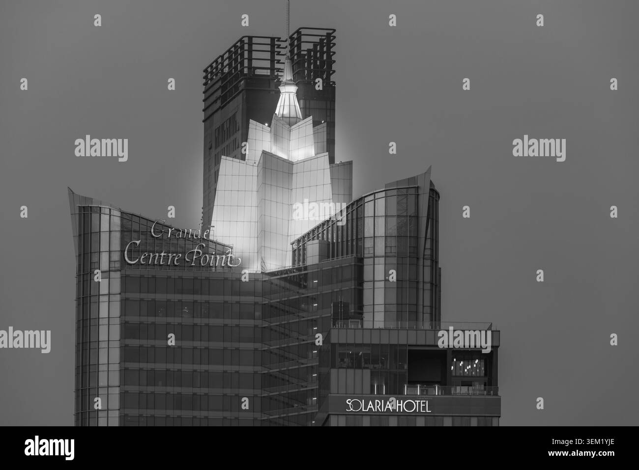 Il grande Centre Point Surawong con la sua corona dorata sorge sopra il quartiere di Bang Rak. L'architettura moderna si illumina di una calda luce serale e di un set Foto Stock
