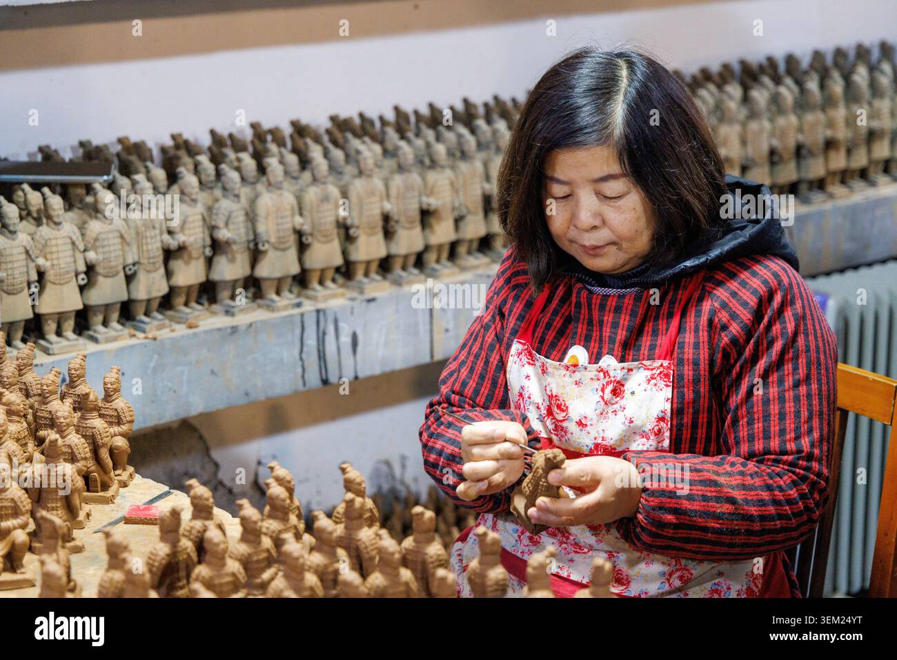 Artigiana cinese che scolpisce le miniature delle repliche dell'esercito di terracotta in un laboratorio presso il Centro esposizioni Arti e Ceramiche di Xi'an, Cina. Foto Stock