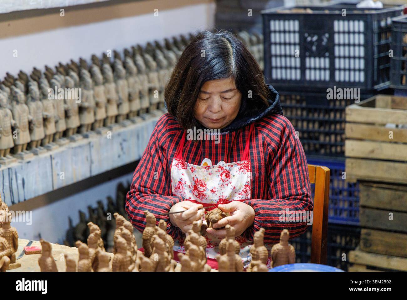 Artigiana cinese che scolpisce le miniature delle repliche dell'esercito di terracotta in un laboratorio presso il Centro esposizioni Arti e Ceramiche di Xi'an, Cina. Foto Stock