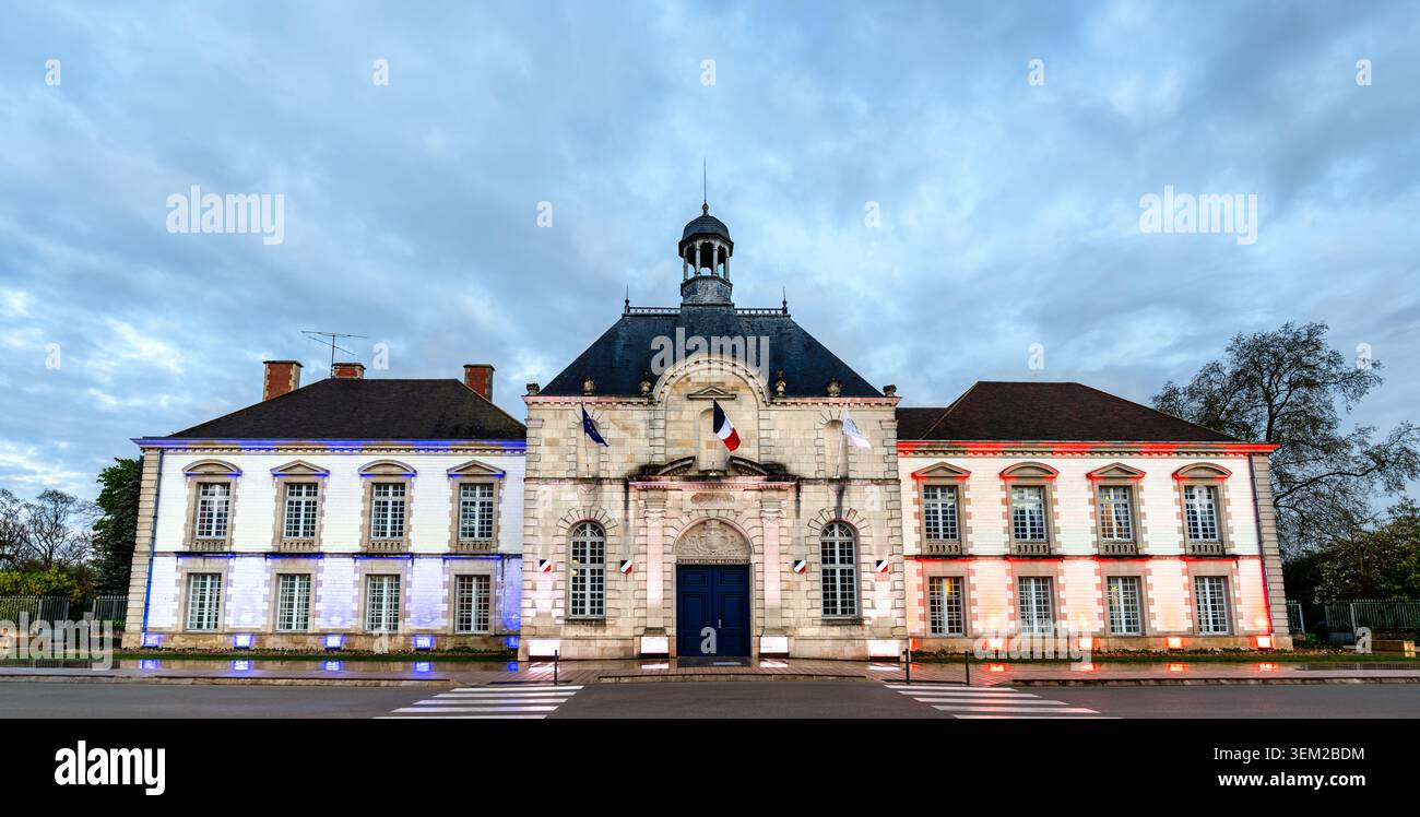 Il municipio di Vitry-le-Francois è illuminato con i colori della bandiera francese sotto un cielo nuvoloso al crepuscolo Foto Stock