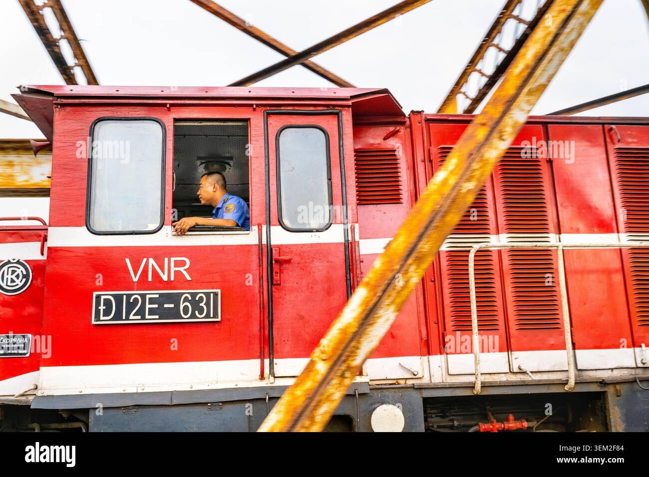 Hanoi, Vietnam - 11 giugno 2025: Un autista di treni ferroviari vietnamiti si avvicina alla stazione ferroviaria di Long Bien, dopo aver attraversato la capriata d'acciaio coloniale francese brid Foto Stock