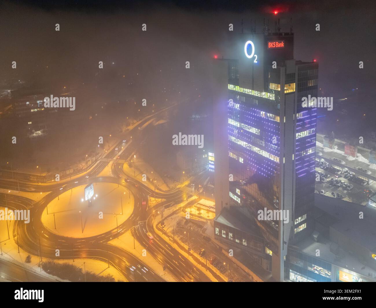 Banska Bystrica, Slovacchia - 7 dicembre 2023: Veduta aerea del grattacielo Europa SC di notte con logo O2 luminoso, atmosfera nebbiosa e illumi Foto Stock