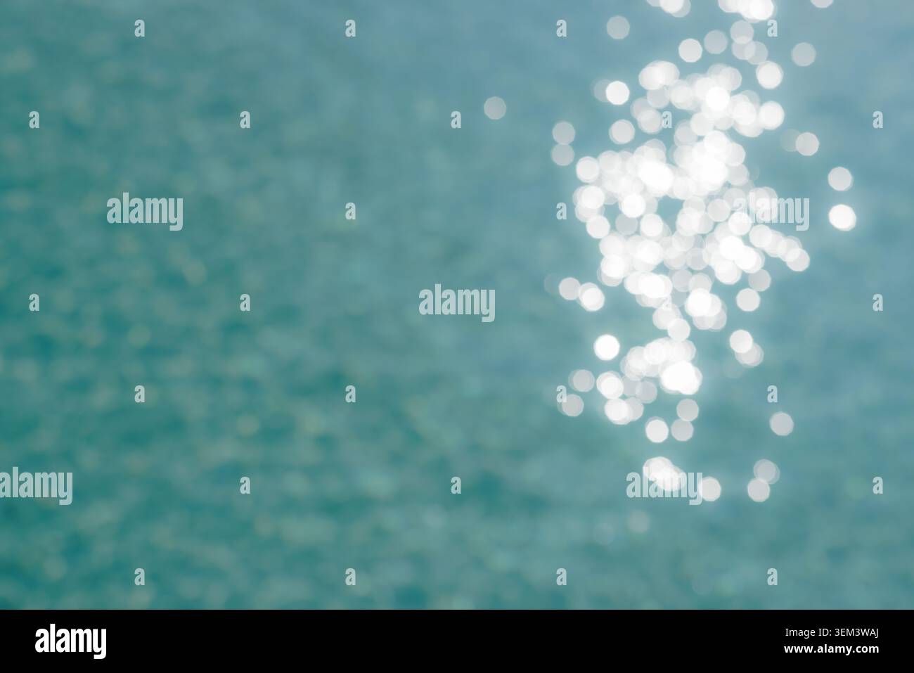 Bokeh di luce solare scintillante sulla superficie calma dell'acqua turchese del mare, astratto. Dettagli di oceano scintillante. Design di sfondo estivo blu naturale tropicale Foto Stock