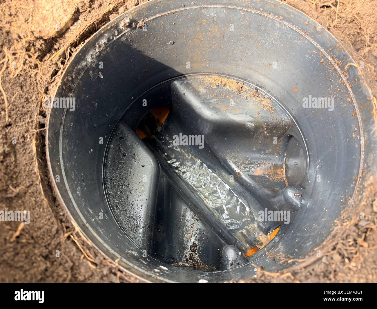 Il tombino domestico aperto rivela l'acqua grigia che passa attraverso i tubi di drenaggio sotterranei che mostrano le infrastrutture di gestione delle acque e delle acque reflue domestiche, IT Foto Stock