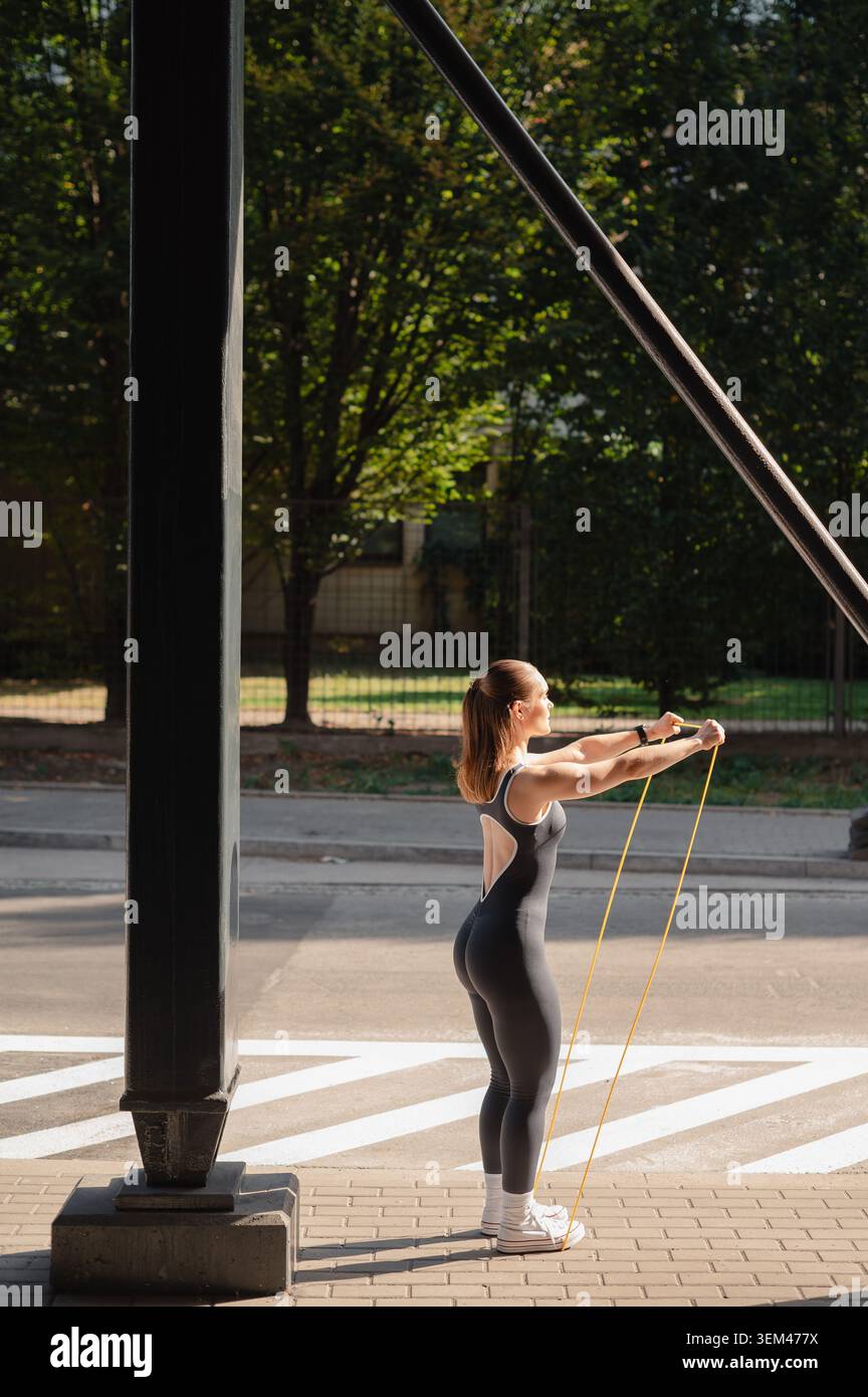 Appassionato di fitness che utilizza bande di resistenza all'aperto vicino a un supporto Foto Stock