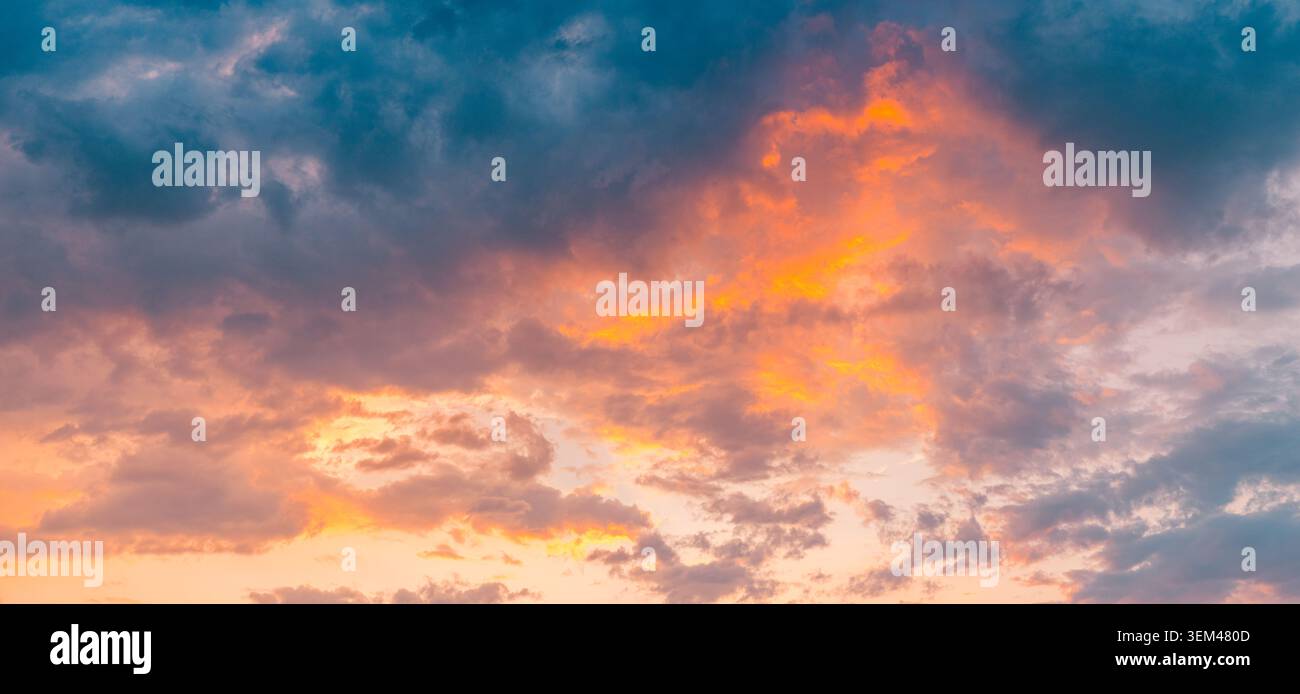 Bagliore arancione infuocato del tramonto che brucia attraverso nuvole tempestose scure e cupe al crepuscolo. Sfondo naturale di nuvole audaci. Sfondo celeste drammatico con spazio per il testo Foto Stock