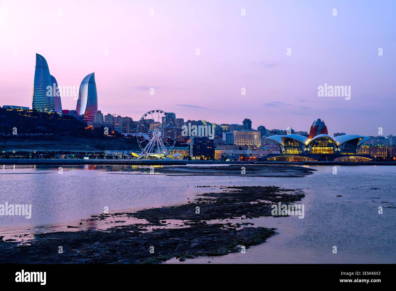 Rovine parzialmente sommerse del castello di Sabayil (1232-1235) nel Mar Caspio con skyline di Baku, Baku Eye e Caspian Waterfront al crepuscolo. Baku, azero Foto Stock