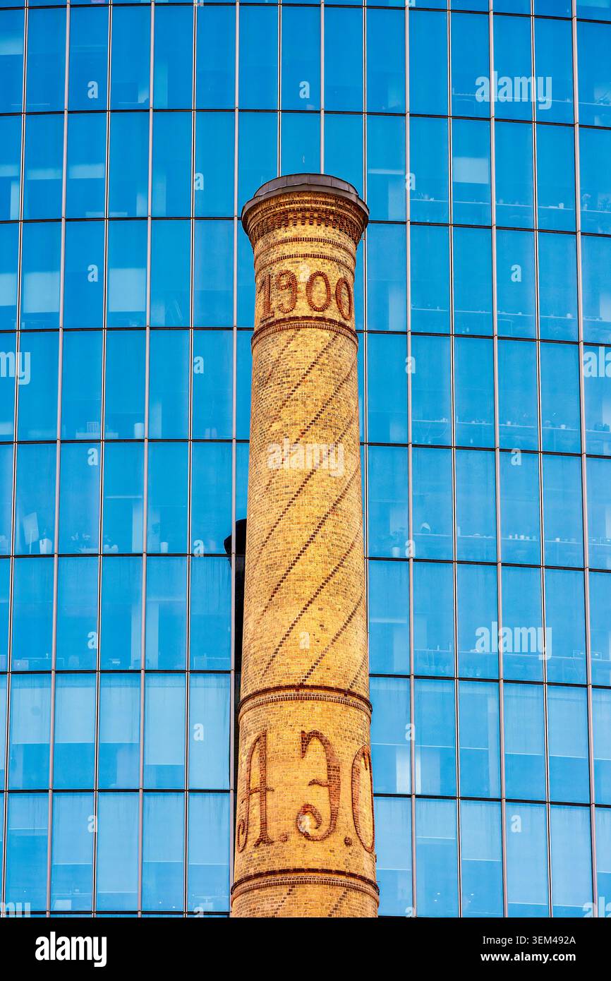 Camino in mattoni dell'epoca dell'olio conservato del 1900 contro la facciata in vetro del complesso di Port Baku, restaurato come punto di riferimento del patrimonio industriale. Baku, Azerbaigian. Foto Stock
