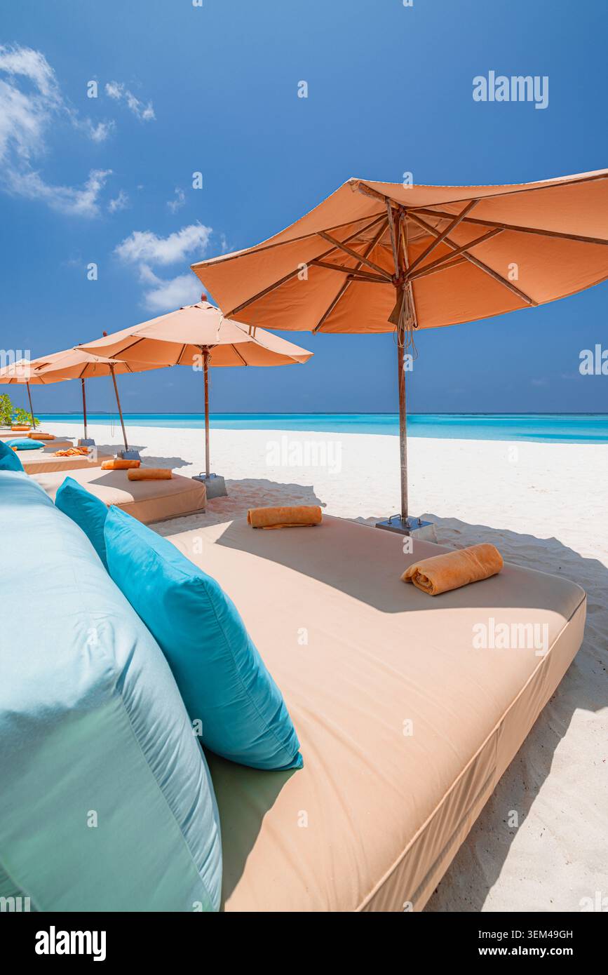 Ombrelloni arancioni rilassanti, fila di lettini, spiaggia di sabbia bianca, oceano turchese, cielo blu. Paesaggio di resort tropicale estivo. Getaway di lusso per luna di miele Foto Stock