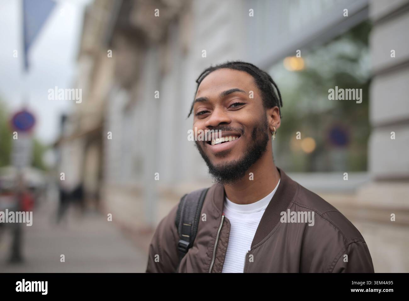 Felice giovane uomo Nero sorridente su una strada di città Foto Stock