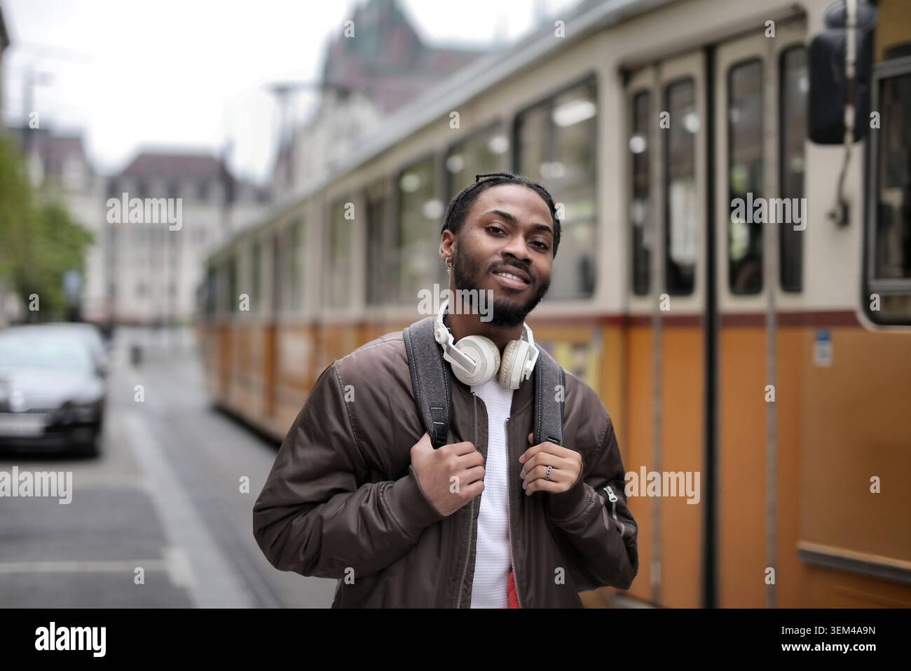 Giovane uomo nero con cuffie sorridenti in tram Foto Stock