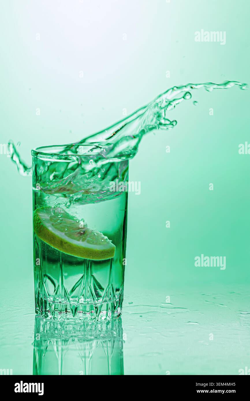Un bicchiere d'acqua con limone. Primo piano su sfondo verde. Foto Stock