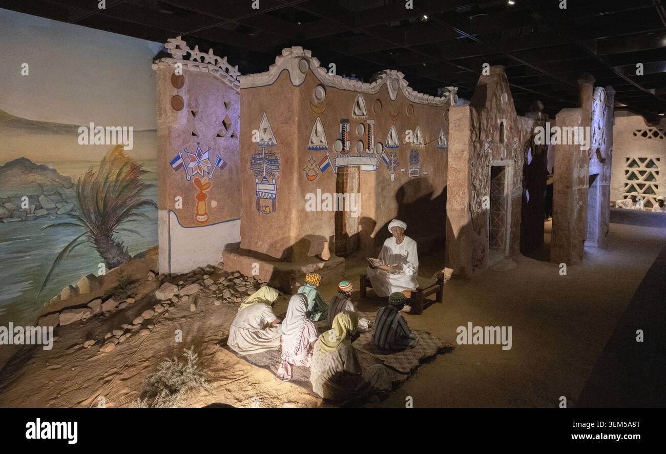 Un diaorama nel Museo Nubiano di Assuan, Egitto, raffigurante un maestro di scuola e sei alunni seduti fuori da una casa decorata tradizionalmente dal Nilo. Foto Stock