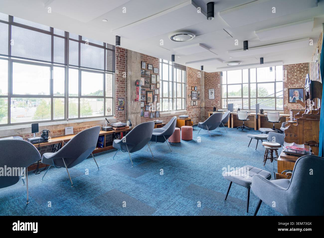 Memphis, Stati Uniti, 24 MAGGIO 2026 - Interno spazioso di un ambiente di lavoro contemporaneo con moquette blu, sedie a sdraio grigie, mattone a vista Foto Stock